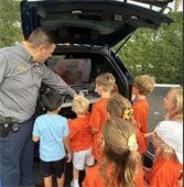 Kids looking at drone in the back of police car